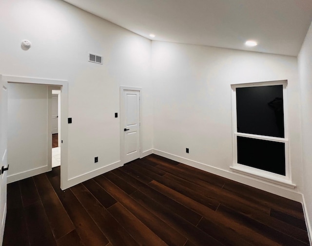 unfurnished room with a towering ceiling and dark hardwood / wood-style flooring