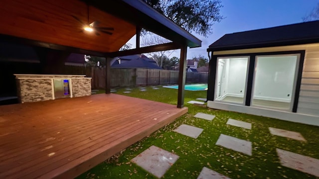 wooden terrace featuring a yard and a fenced in pool