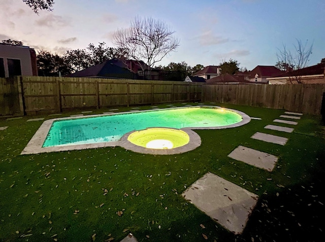 pool at dusk featuring an in ground hot tub and a yard