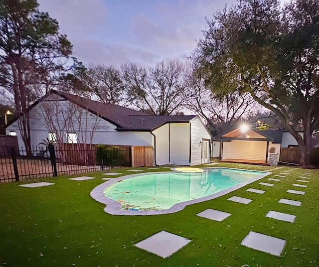 pool at dusk with a lawn and an outdoor structure