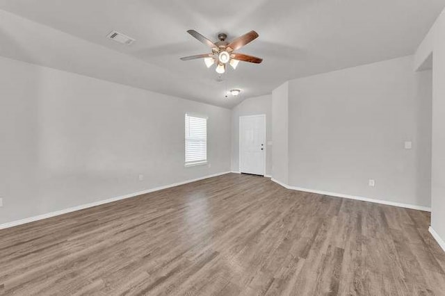 empty room featuring hardwood / wood-style flooring, vaulted ceiling, and ceiling fan