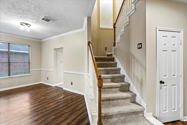 stairs featuring baseboards, visible vents, ornamental molding, wood finished floors, and a textured ceiling