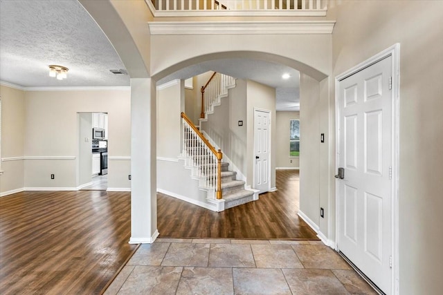 foyer entrance featuring arched walkways, baseboards, and wood finished floors