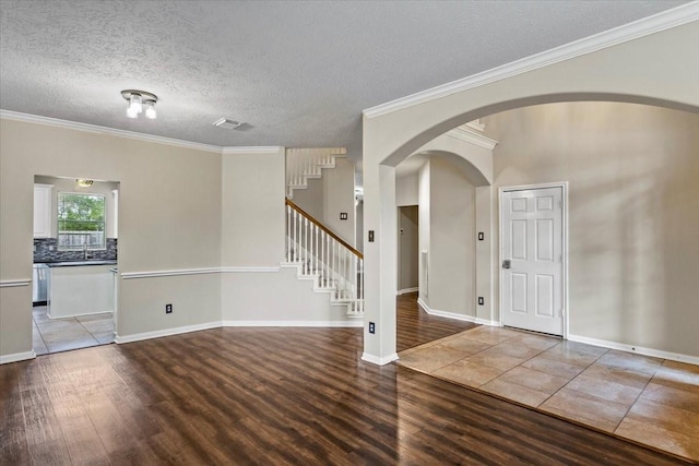 entryway with wood finished floors, visible vents, baseboards, stairs, and crown molding