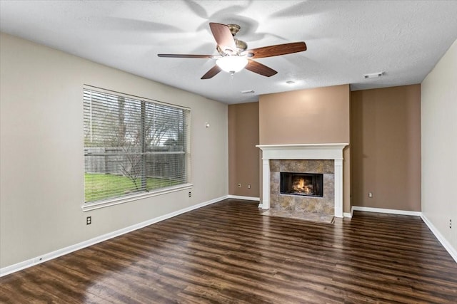 unfurnished living room with dark wood-style floors, baseboards, visible vents, and a tile fireplace