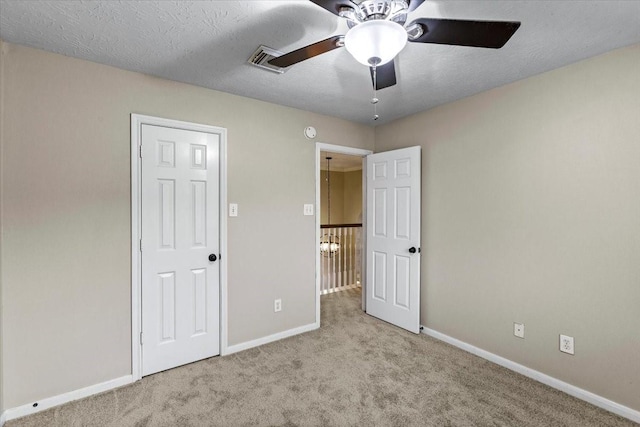 unfurnished bedroom featuring baseboards, a textured ceiling, and light colored carpet