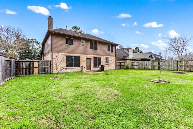 back of property with brick siding, a lawn, a chimney, and a fenced backyard