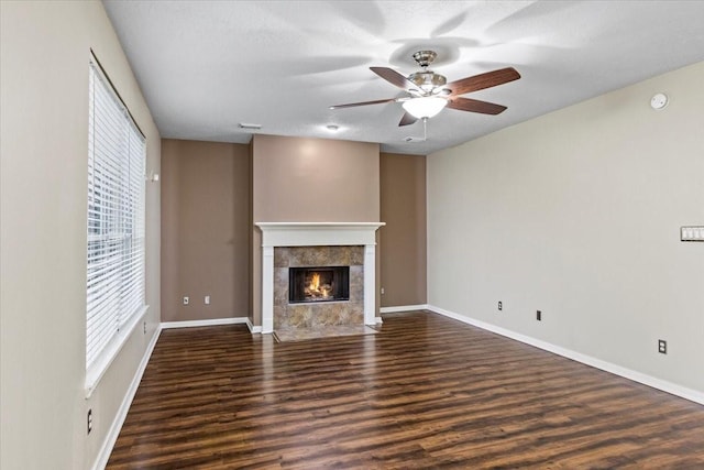 unfurnished living room featuring baseboards, a ceiling fan, a tiled fireplace, dark wood-style flooring, and a textured ceiling