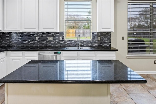 kitchen with tasteful backsplash, white cabinets, dishwasher, dark stone countertops, and a sink