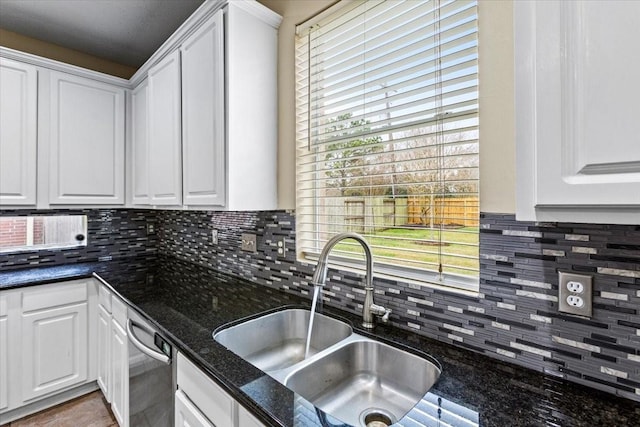 kitchen featuring dark stone countertops, white cabinets, and a sink