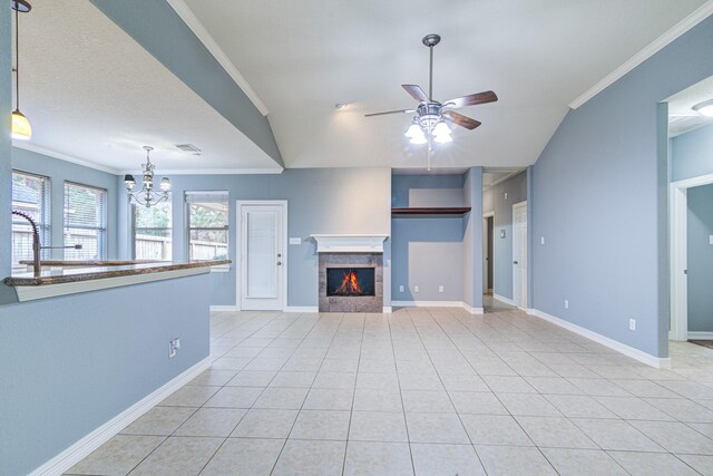 unfurnished living room featuring light tile patterned floors, a warm lit fireplace, ceiling fan with notable chandelier, and crown molding