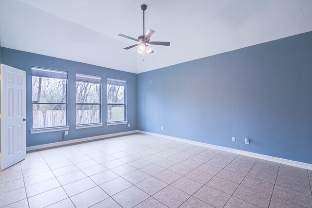 empty room with vaulted ceiling, ceiling fan, baseboards, and light tile patterned floors