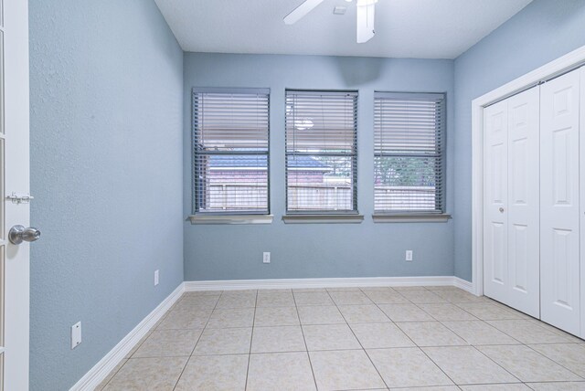 unfurnished bedroom featuring light tile patterned floors, ceiling fan, a closet, and baseboards