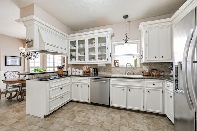 kitchen with appliances with stainless steel finishes, pendant lighting, sink, dark stone countertops, and white cabinets