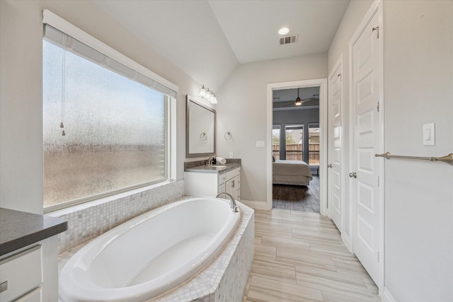 bathroom with vanity and tiled tub