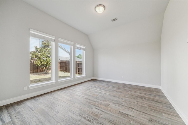 empty room with lofted ceiling and light hardwood / wood-style flooring