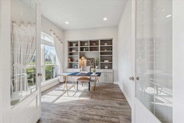 office with plenty of natural light, hardwood / wood-style floors, and french doors