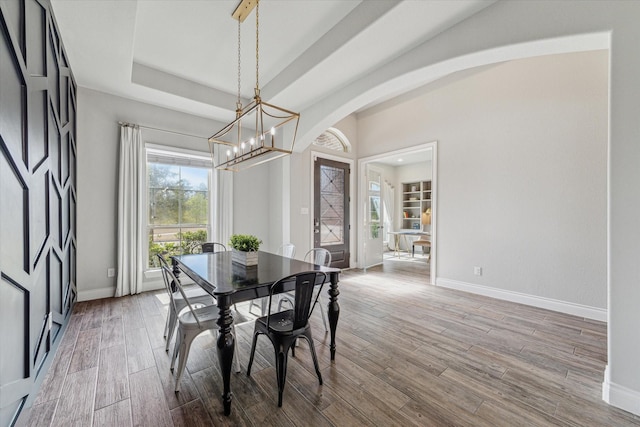 dining space featuring a tray ceiling, wood-type flooring, and a chandelier