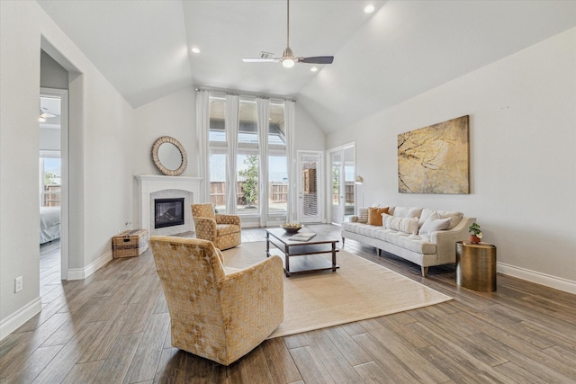 living room with hardwood / wood-style flooring, a premium fireplace, vaulted ceiling, and ceiling fan