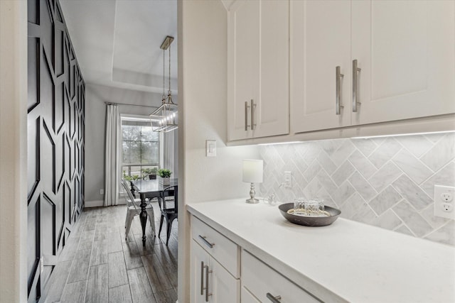 kitchen featuring pendant lighting, backsplash, light wood-type flooring, and white cabinets