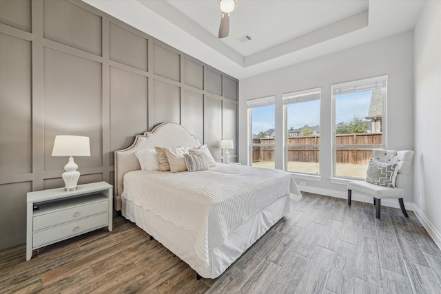 bedroom featuring ceiling fan, dark hardwood / wood-style floors, and a raised ceiling