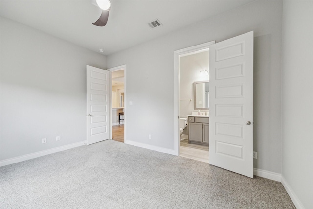 unfurnished bedroom featuring light carpet, sink, ceiling fan, and ensuite bathroom