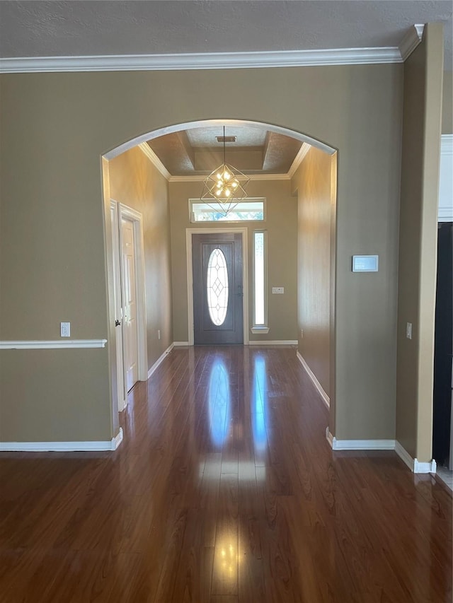 foyer entrance with arched walkways, crown molding, baseboards, and wood finished floors