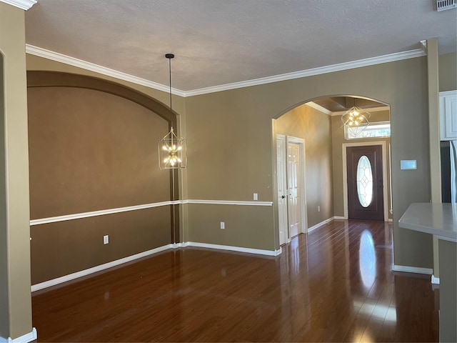 foyer featuring ornamental molding, a notable chandelier, baseboards, and wood finished floors