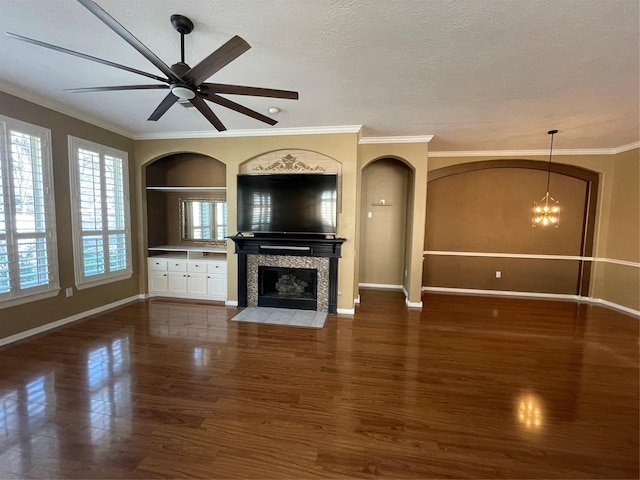 unfurnished living room with built in features, a fireplace, ornamental molding, a textured ceiling, and wood finished floors