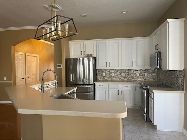 kitchen with arched walkways, a kitchen island with sink, a sink, visible vents, and appliances with stainless steel finishes