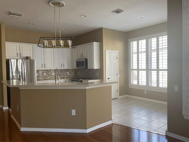 kitchen featuring light countertops, appliances with stainless steel finishes, visible vents, and decorative backsplash