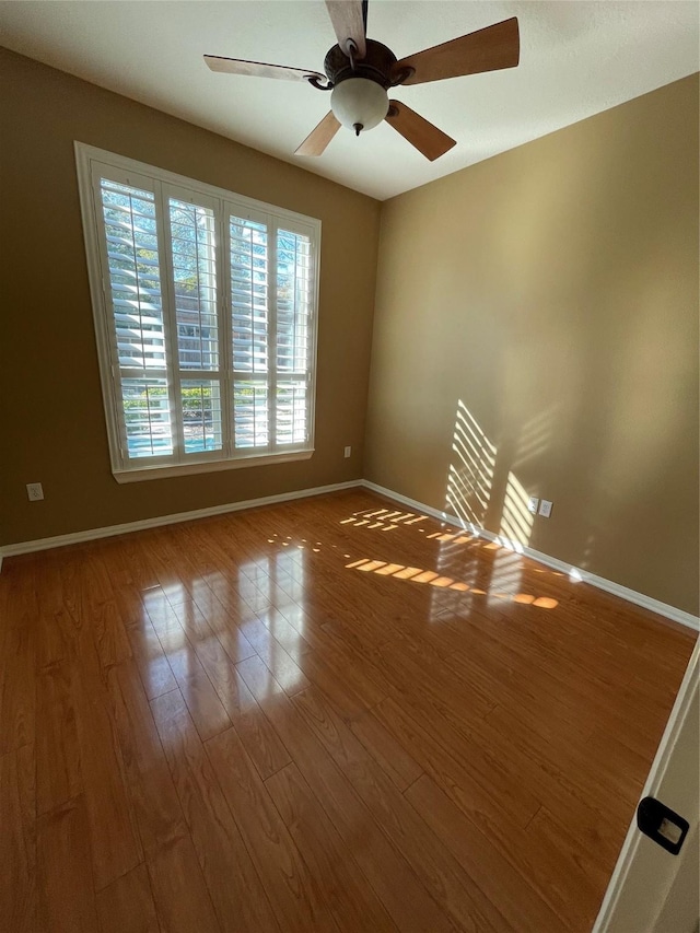 empty room with ceiling fan, baseboards, and wood finished floors