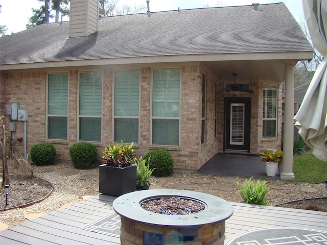 doorway to property with a shingled roof, brick siding, and a chimney