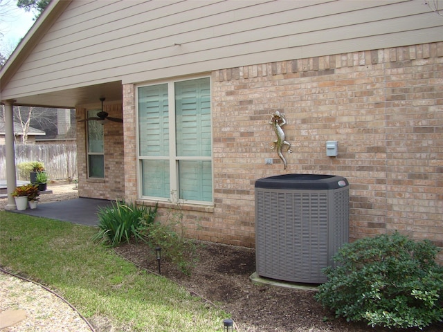 details featuring fence, central AC, and brick siding