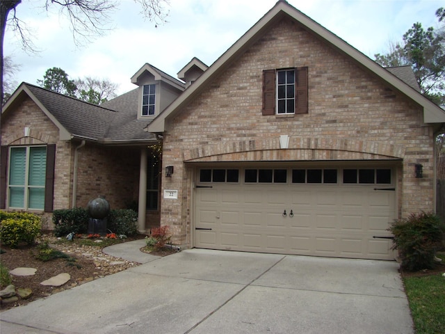 view of front of house featuring a shingled roof, concrete driveway, and brick siding