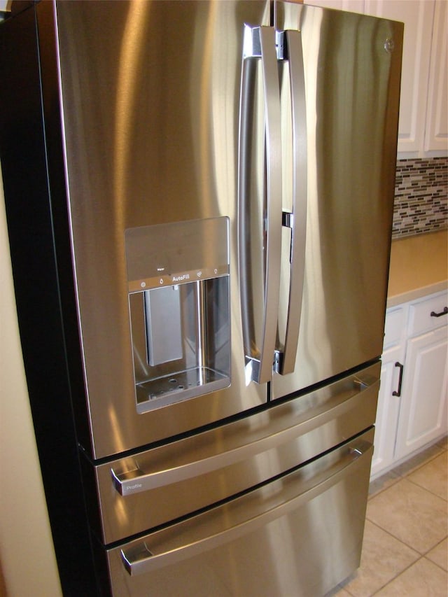 details featuring decorative backsplash, light countertops, white cabinetry, and stainless steel fridge with ice dispenser