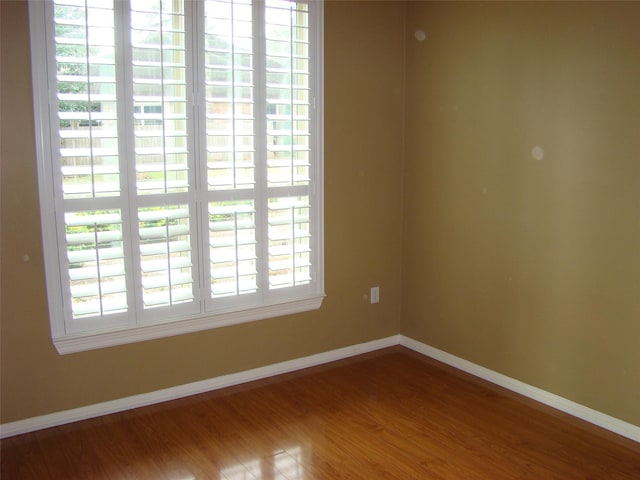 spare room with wood finished floors and baseboards