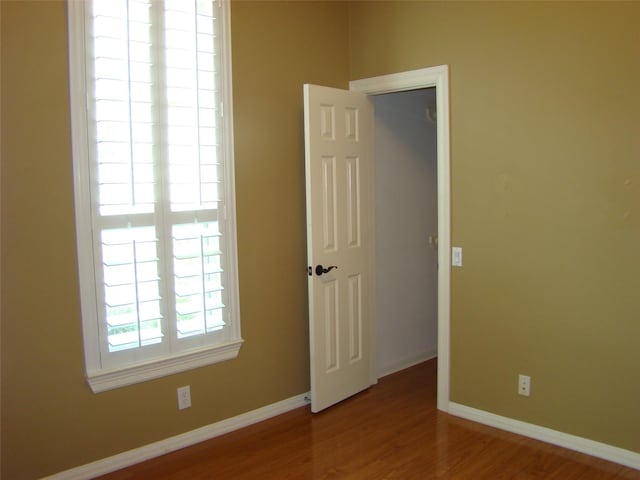 spare room featuring baseboards and wood finished floors