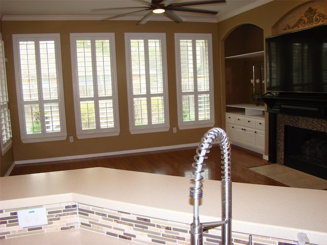 kitchen with ornamental molding, a high end fireplace, a ceiling fan, white cabinets, and wood finished floors