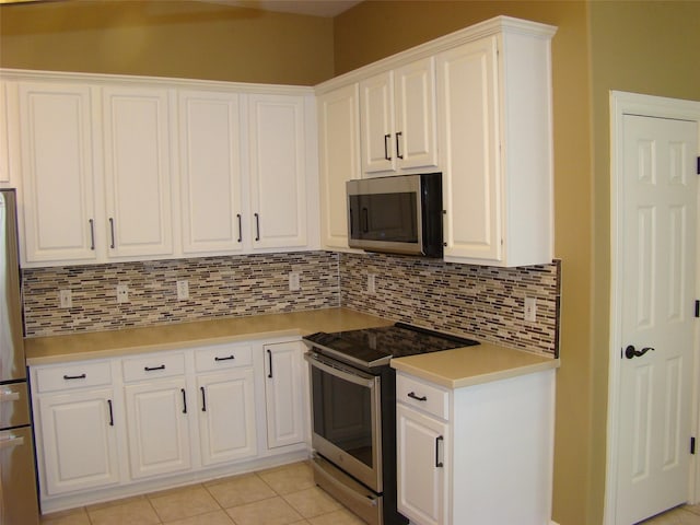 kitchen featuring light tile patterned flooring, stainless steel appliances, white cabinets, light countertops, and backsplash