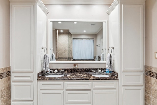 bathroom featuring double vanity, tile walls, a sink, and ornamental molding