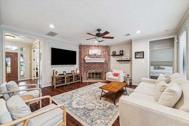 living area featuring ornamental molding, dark wood-type flooring, a fireplace, and visible vents