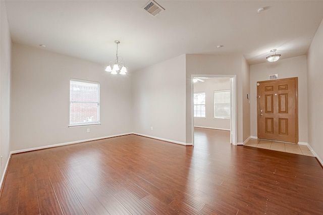 spare room featuring hardwood / wood-style floors and a notable chandelier