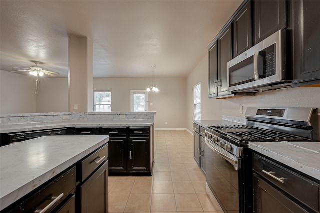 kitchen with decorative light fixtures, a wealth of natural light, stainless steel appliances, and light tile patterned flooring