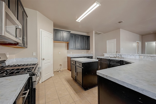 kitchen featuring light tile patterned floors, sink, a center island, and appliances with stainless steel finishes