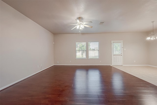 spare room featuring dark hardwood / wood-style floors and ceiling fan with notable chandelier