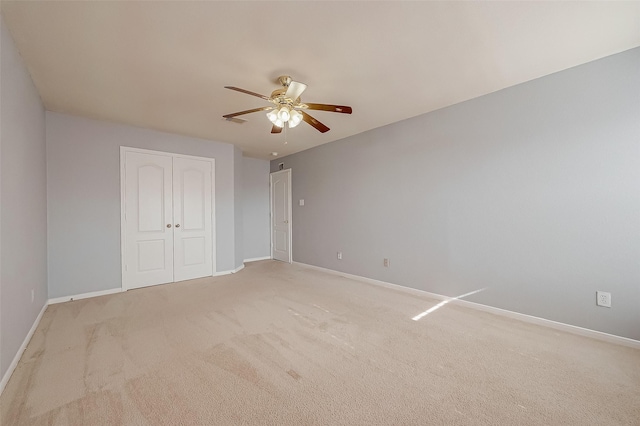 unfurnished bedroom with light carpet, ceiling fan, and a closet