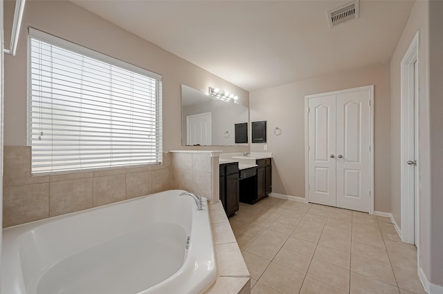 bathroom featuring tile patterned flooring, vanity, and a relaxing tiled tub