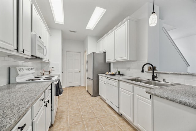 kitchen featuring light tile patterned floors, white appliances, white cabinetry, and a sink