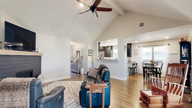 living room with hardwood / wood-style flooring, ceiling fan, high vaulted ceiling, and beamed ceiling